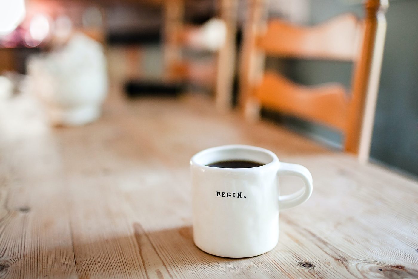 A white mug printed with the word Begin on a wooden table