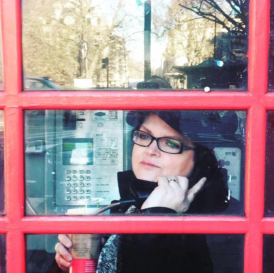 Martta Eicher Rabago smiling on the phone inside a red telephone box