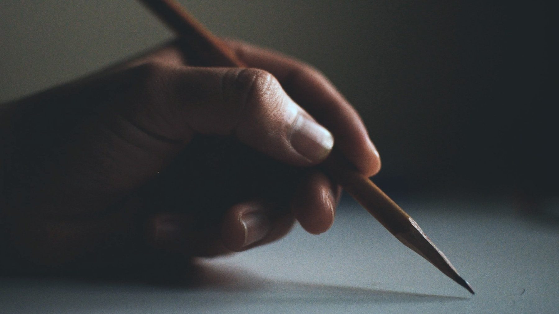 A hand holding a pencil over a sheet of paper