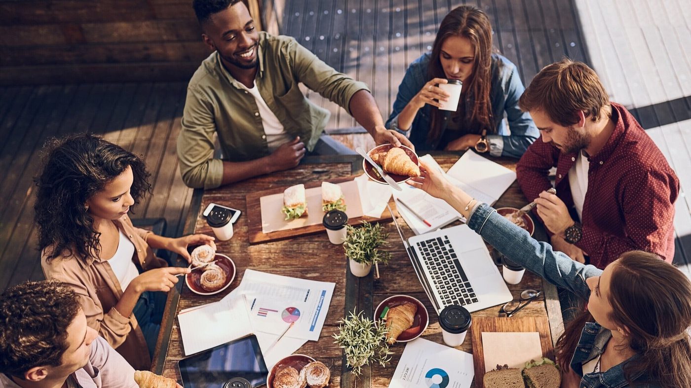 A team gathered around a wooden table with laptops, notes and coffee